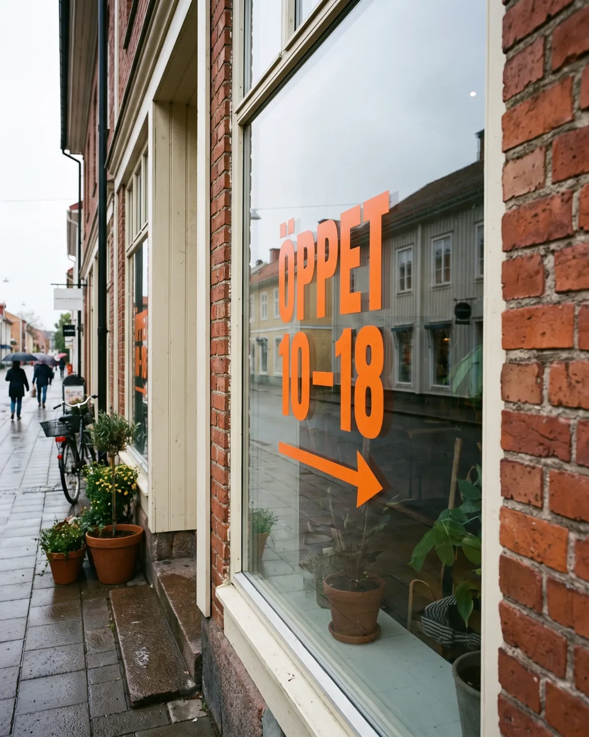 Orange skuren vinyltext med öppettider på en butiksruta.